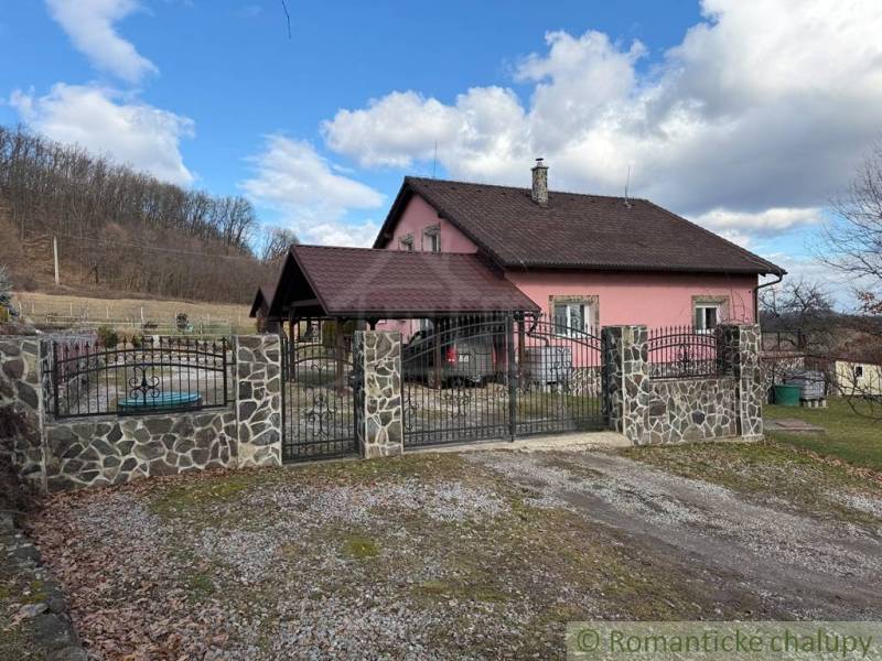 A family house in Lukovištia with a pink facade, a stone fence, and a gate.