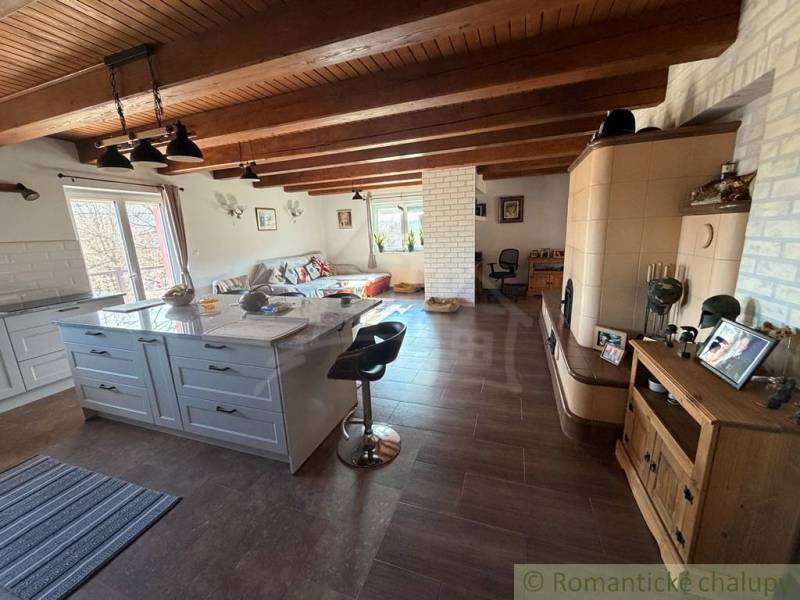 Interior of a family house with ceiling beams, kitchen, living room, and floor with wooden decor.