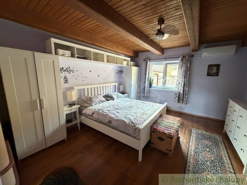 A bedroom in a family house with a wooden decor floor and a floral pattern on the wall.