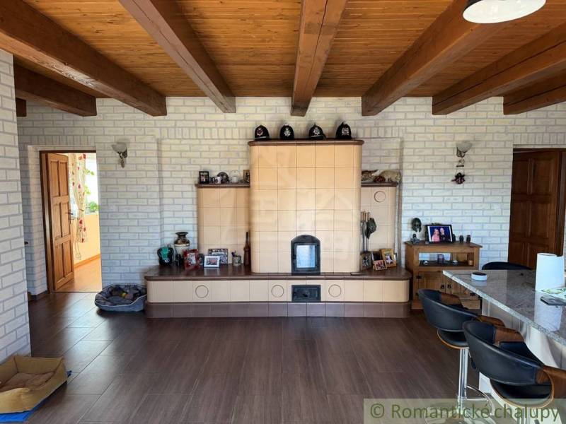 Interior of a family house with a tiled stove, decorative wooden beams, and a floor with a wooden design.