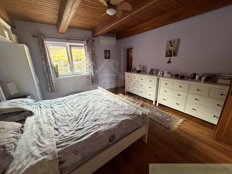 Bedroom in a family house with wooden beams and a floor with a wooden decor, furnished with a bed.