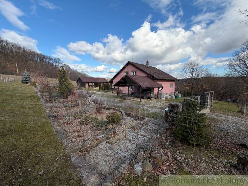 A family house in Lukovištia surrounded by nature, trees, a path, blue sky, clouds.