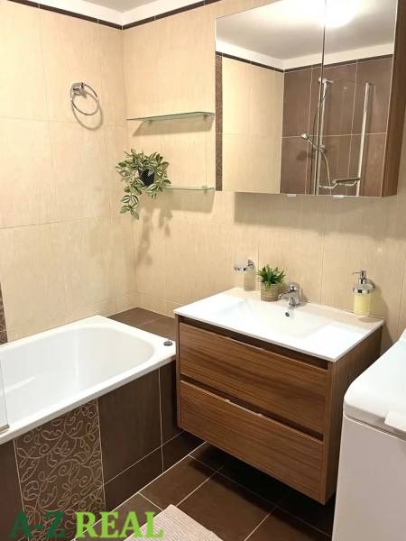 Bathroom in a 3-room apartment with a bathtub, wooden decor, and a sink with a mirror.