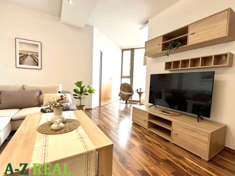Living room in a three-room apartment with a wooden decor floor and simple furnishings.