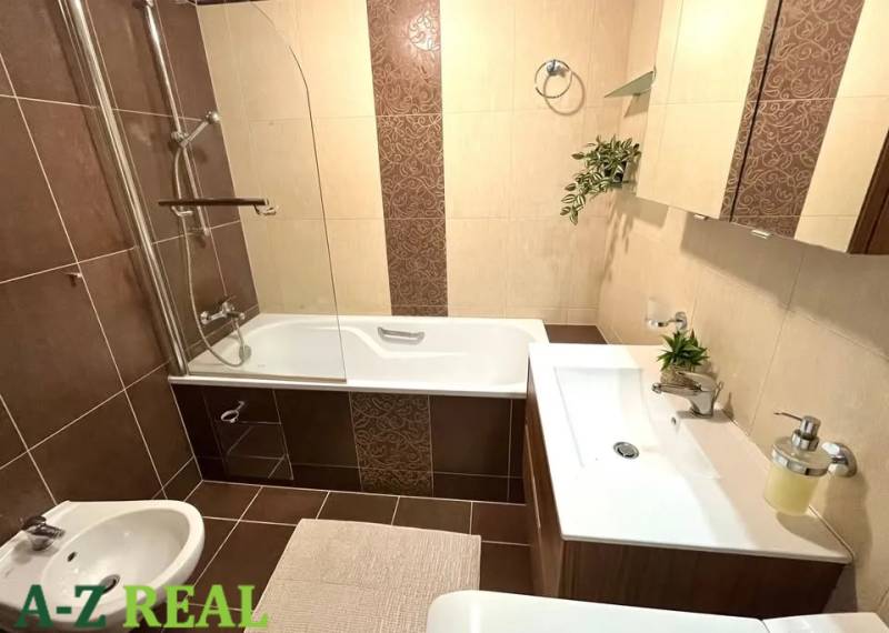 A bathroom in a 3-room apartment with a bathtub, sink, and decorative tiles.