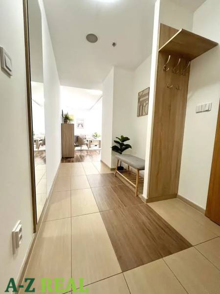 Entrance hall in a 3-room apartment with tiles and a bench, leading to the living room.