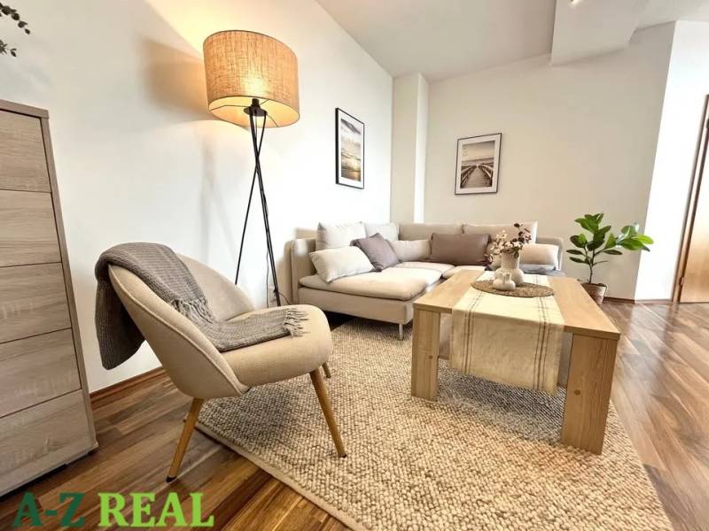 Living room in a 3-room apartment with a wooden decor floor, comfortable seating, and a lamp.