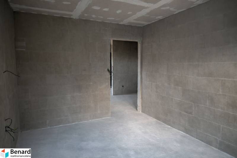A room in a 3-room apartment with gray walls and ceiling. Bare floors.
