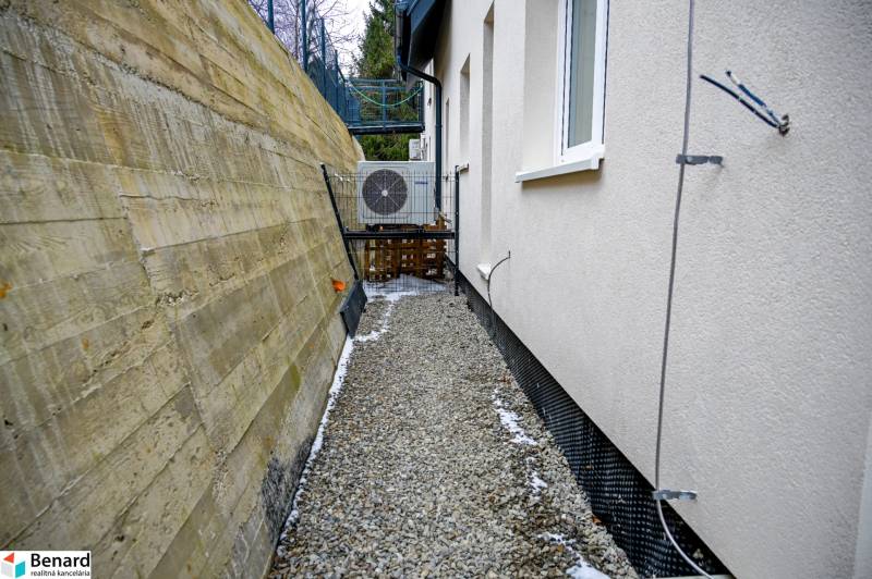 A narrow passage between a building and a retaining wall with air conditioning in Stará Ľubovňa.
