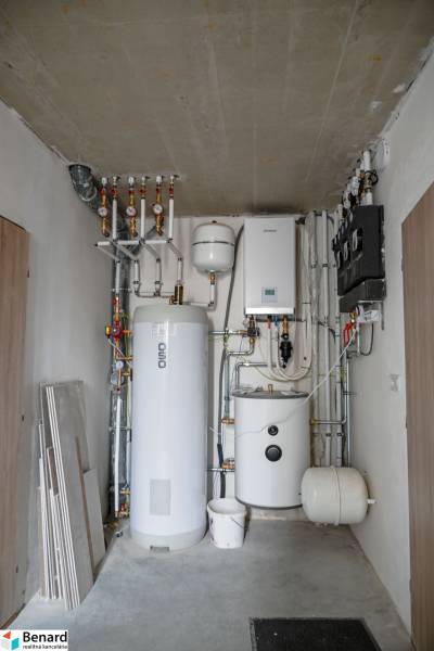 Technical room with a boiler and a furnace, visible pipes and measuring instruments.