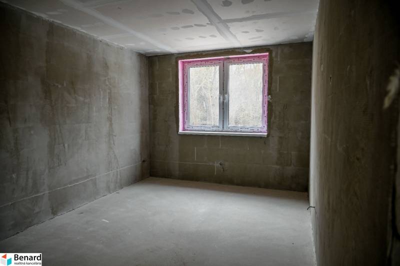 Unfinished room with a window and concrete floor in a 3-room apartment.