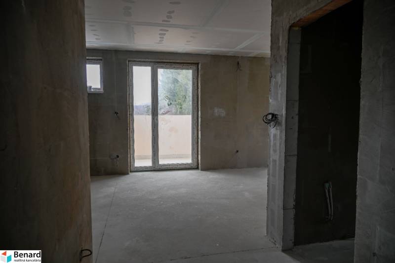 Unfinished interior of a 3-room apartment with large windows and concrete floor.