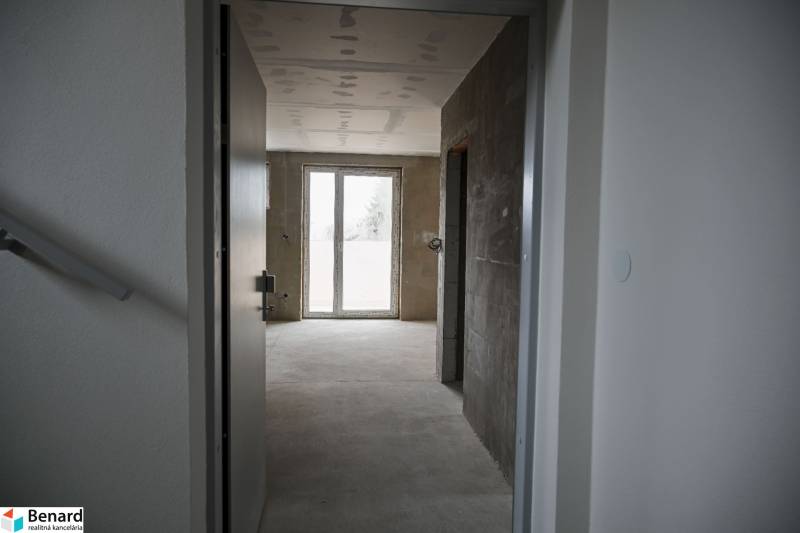 Interior of a 3-room apartment with a concrete floor and a large French window.