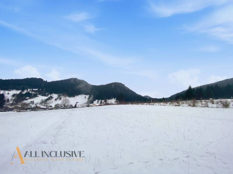 Snow-covered lands in Komjatná with a view of the surrounding mountains and blue sky.