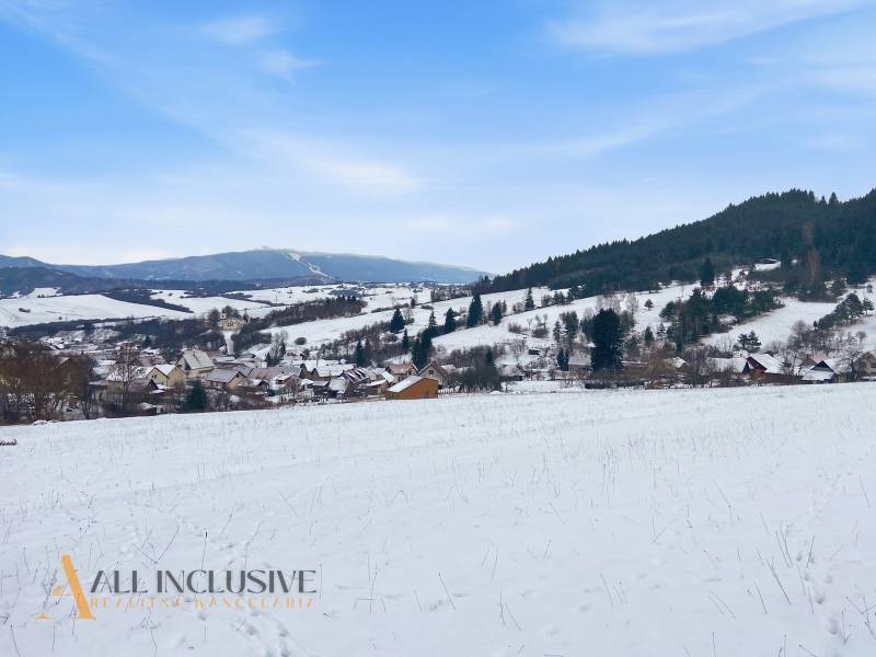 Snowy landscape of Komjatná with a view of dwellings and hills, suitable for plots - housing.