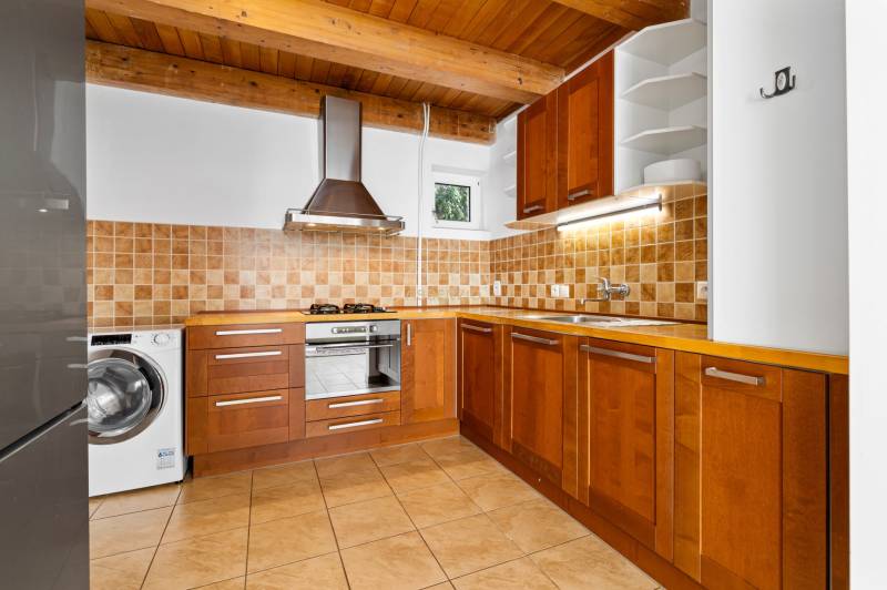 A kitchen in a family house with wooden decor, ceramic tiles, and built-in appliances.