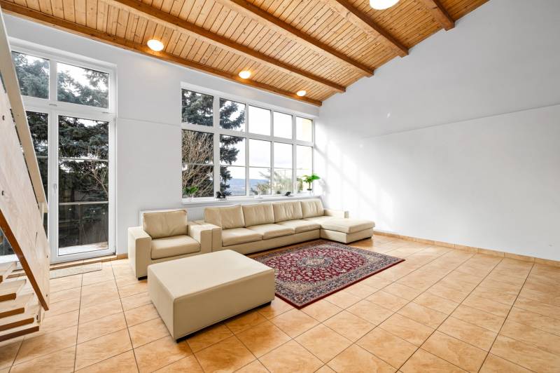 Living room in a family house with a cream sofa, large windows, and ceramic tiles.
