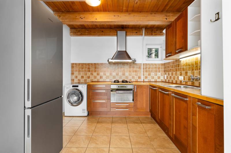 A kitchen in a family house with wooden cabinets, a floor with a wooden decor, appliances.