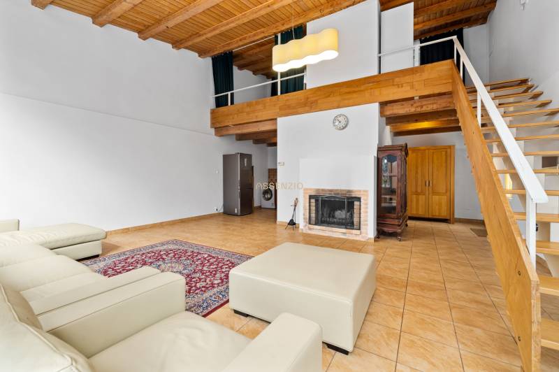 Living room with a fireplace, leather sofa, stone tiles, and wooden ceiling in a family house.