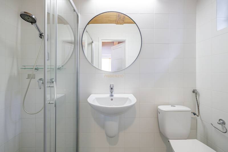 Bathroom with a round mirror, shower, and sink in a family house.