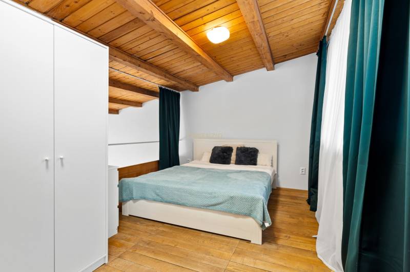 Bedroom with a double bed, storage wardrobe, and wooden decor flooring in a family house.