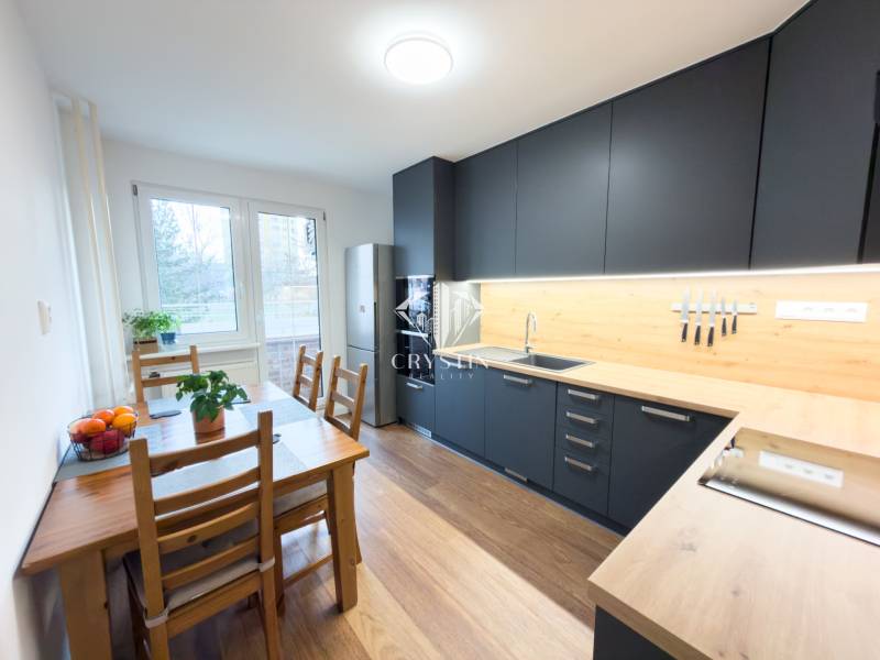 A kitchen in a 4-room apartment with a wooden decor floor and a dining table.