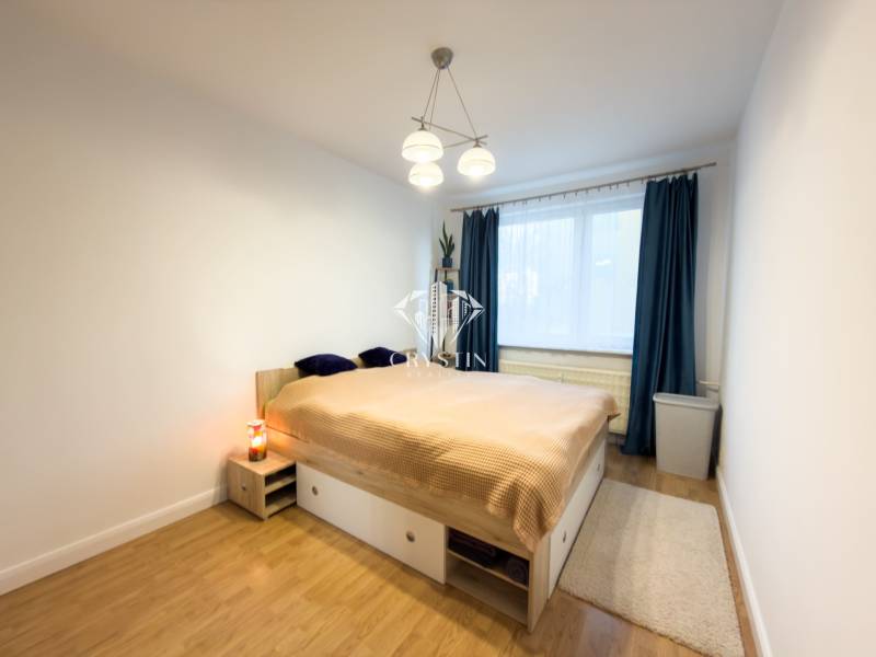 Bedroom in a 4-room apartment with a bed, wood-patterned flooring, and curtains.