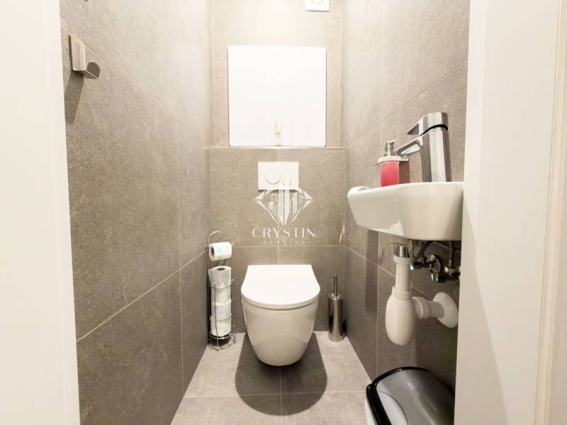 A small bathroom in a 4-room apartment with dark gray tiles and white sanitary fixtures.
