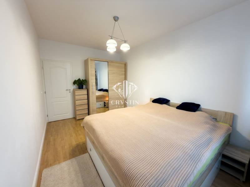 Bedroom in a 4-room apartment with a spacious bed, wardrobe, and wooden decor flooring.