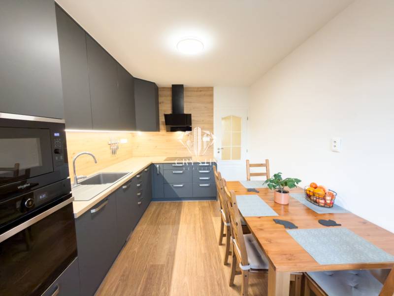 A kitchen in a 4-room apartment with a wooden decor floor and modern furniture.