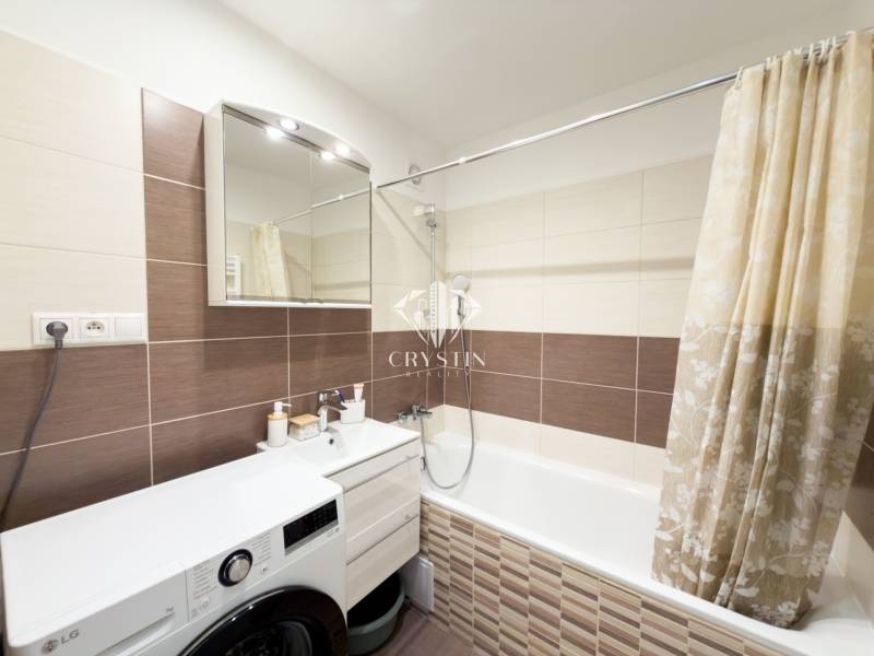 Bathroom in a 4-room apartment with a bathtub, washing machine, and subtle wall tiles.