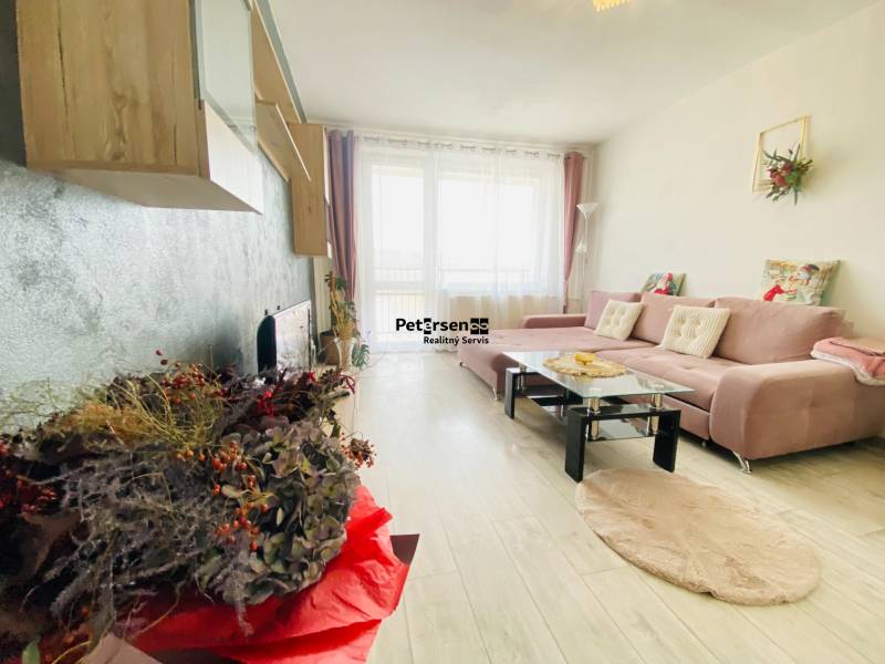 Living room in a three-room apartment with a wooden decor floor and a comfortable corner sofa.