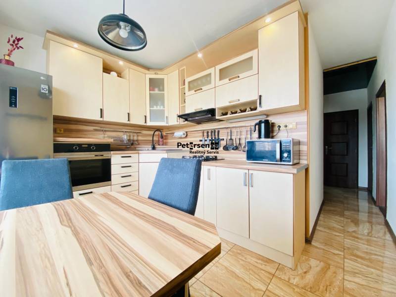 A kitchen in a 3-room apartment with wooden decor, a table, and modern appliances.