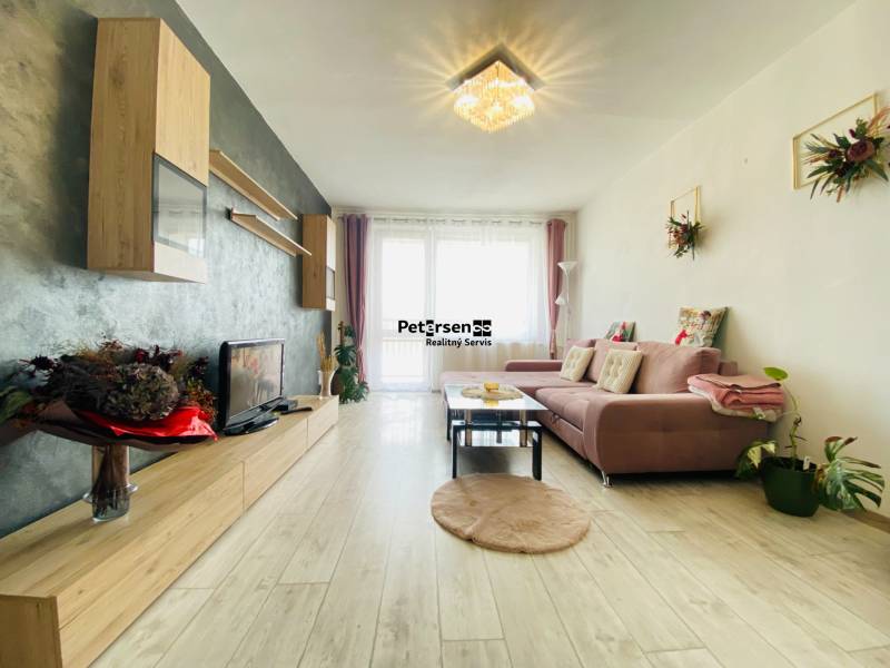 Living room in a three-room apartment with a wooden decor floor and a comfortable sofa.