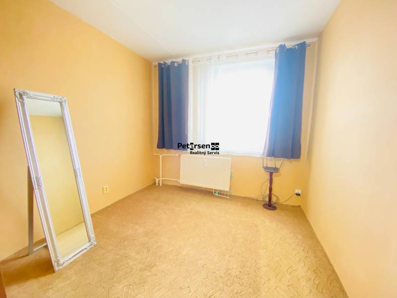 A room in a 3-room apartment with a mirror, curtains, and a radiator.