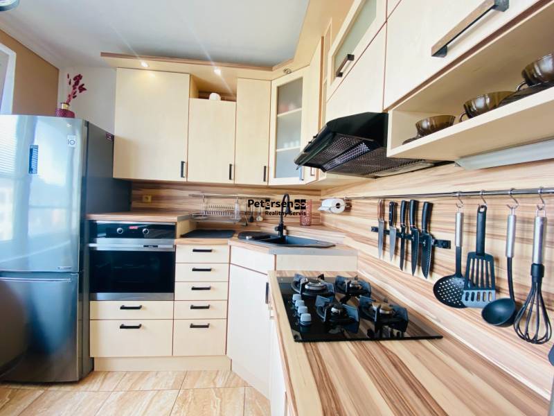 A kitchen in a 3-room apartment with stainless steel appliances and a wood-patterned floor.