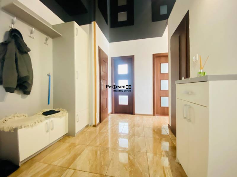 A hallway with a shiny floor and a coat rack in a 3-room apartment.