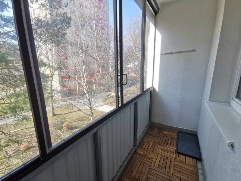 Enclosed balcony with a view of greenery, 2-room apartment, floor with wood decor.