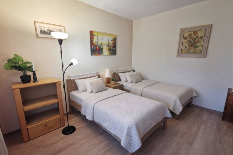 Double bedroom with wood-patterned flooring in a two-room apartment, cozy beds.