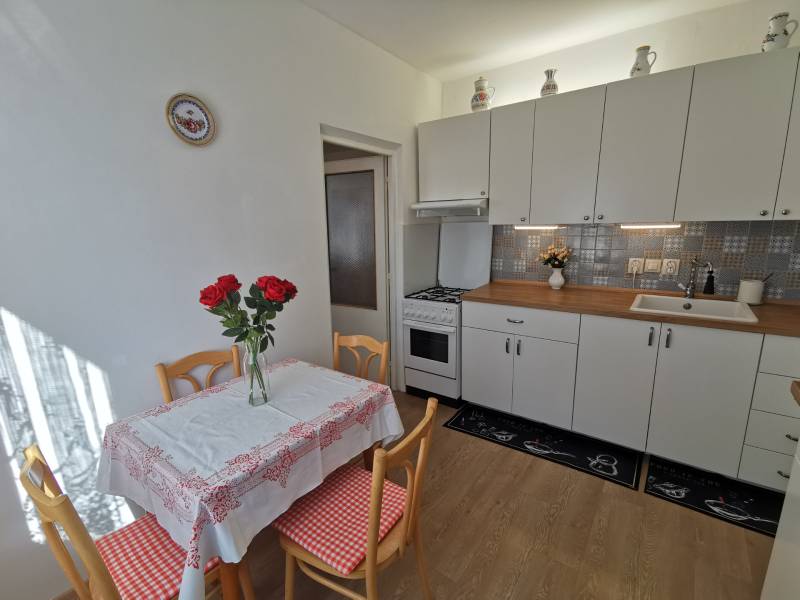 A kitchen in a 2-room apartment with white cabinets and a table with red details.