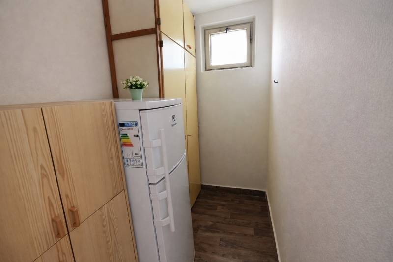 A narrow space in a 2-room apartment with a wardrobe, a freezer, and a wooden decor floor.