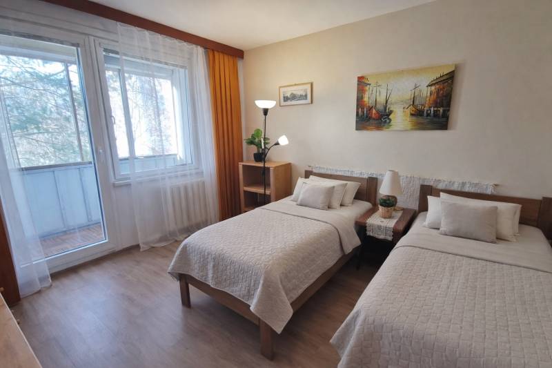 Double bedroom in a 2-room apartment with a balcony and a wooden decor floor.