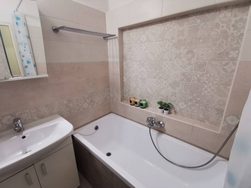 A bathroom in a 2-room apartment with a bathtub and decorative tiles.