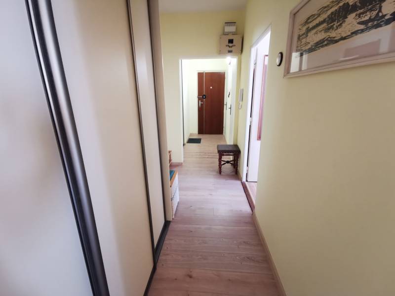 A hallway in a 2-room apartment with a wooden decor floor and a built-in wardrobe.