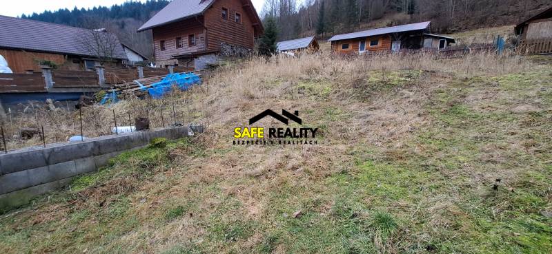 Land in Oščadnica designated for residential use with visible wooden structures on sloping terrain.