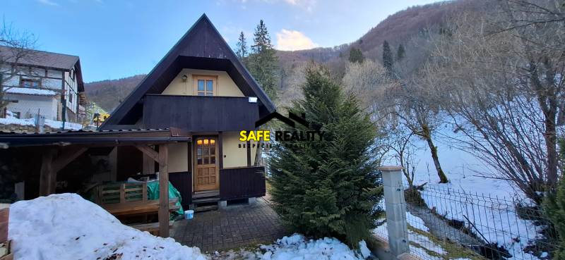 A wooden cabin in the snowy area of Poviny with a shelter and a winter atmosphere.