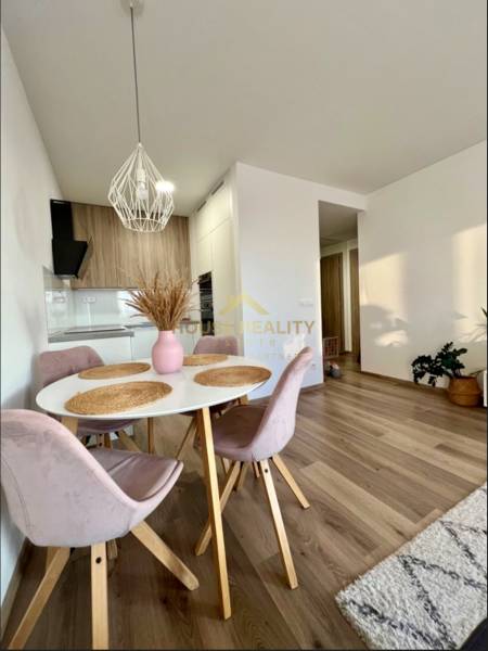 Dining area in a 2-room apartment with a wood-patterned floor and a pendant light.
