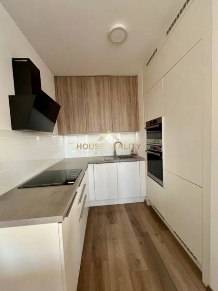 A kitchen in a 2-room apartment with a wooden decor floor and built-in appliances.