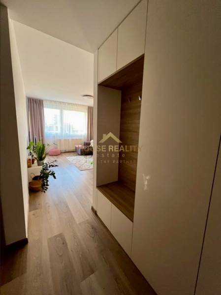 A hallway in a 2-room apartment with a wooden decor floor and light furniture.