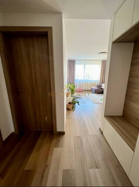 A hallway of a 2-room apartment with a wooden decor floor, leading to a bright living room.